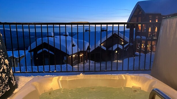 Ein Whirlpool mit Blick auf schneebedeckte Gebäude und ein Gewässer im Hintergrund.