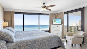 A hotel room with a large bed, a ceiling fan, a TV, a balcony with a view of the ocean, and a chair. - 11th Floor, Beachfront, BEST BEACH, Amazing Views, Beachside 1, Sandestin! (Miramar Beach)
