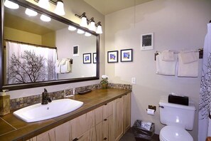 A bathroom with a large mirror, a sink, a toilet, and a trash bin. - Steps Away from Adventure! Ski-In/Ski-Out Condo, Dog Friendly (Mt. Crested Butte)
