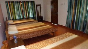A hotel room with a large bed, a wooden bench, and a small table with a bottle. - Wilpattu Dilsara Holiday Resort (Pahala Maragahawewa)
