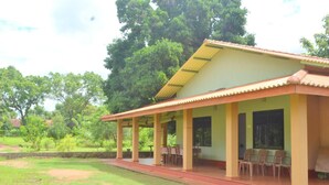 A building with a covered patio area, a dining table, and chairs. - Wilpattu Dilsara Holiday Resort (Pahala Maragahawewa)