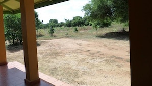 An outdoor area with a covered patio, a dirt ground, and surrounding greenery. - Wilpattu Dilsara Holiday Resort (Pahala Maragahawewa)