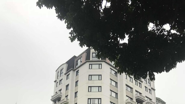 Ein mehrstöckiges Hotel mit einem Starbucks Coffee im Erdgeschoss, umgeben von Bäumen und belebter Straße.