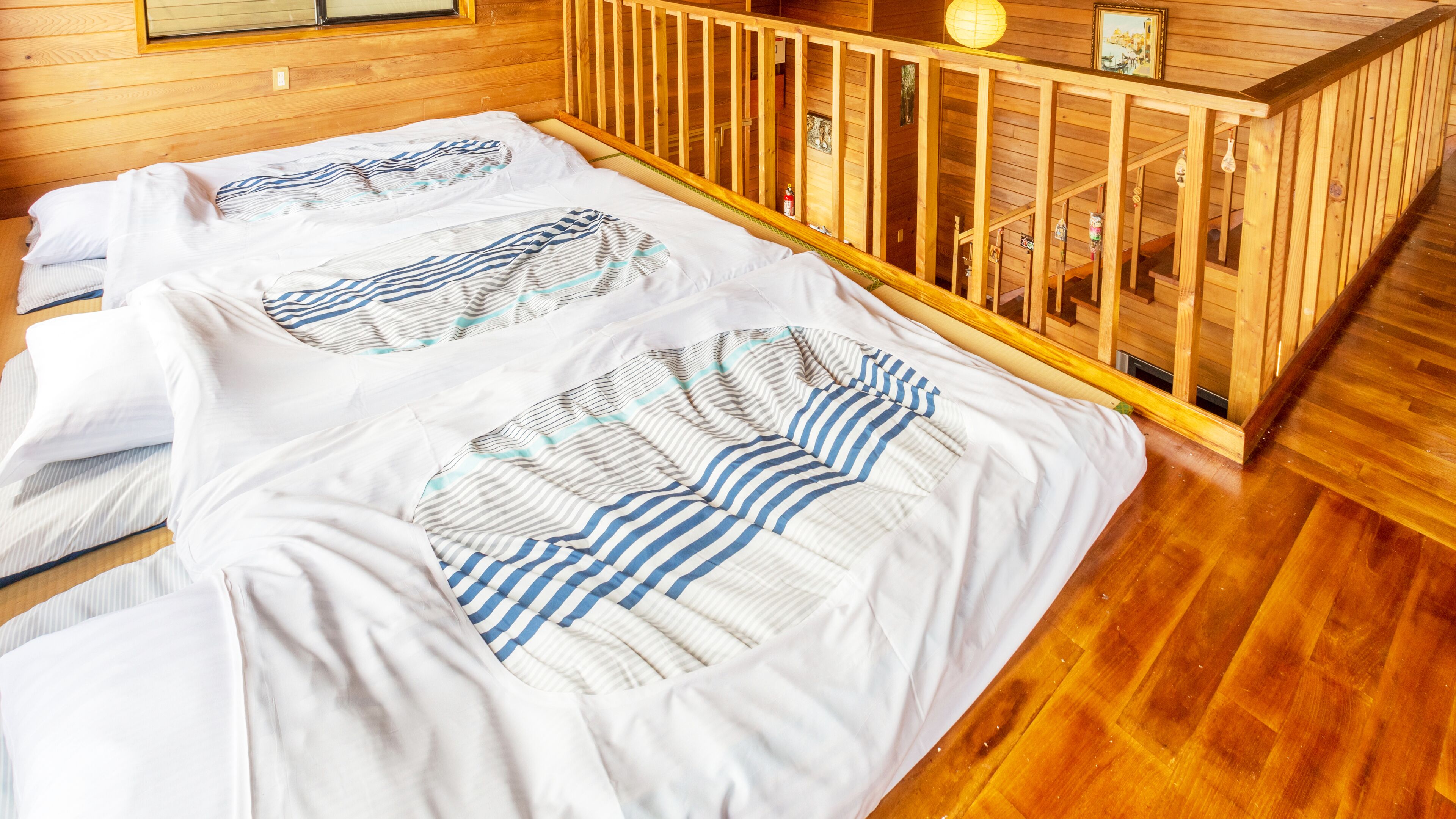 A wooden cabin room with a bed covered in striped bedding.