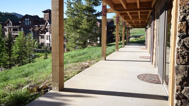 A covered walkway with stone pillars and a view of residential buildings and trees. - Great Location=Great Vacation. Dog Friendly Condo w/ Awesome Ski Access (Mt. Crested Butte)