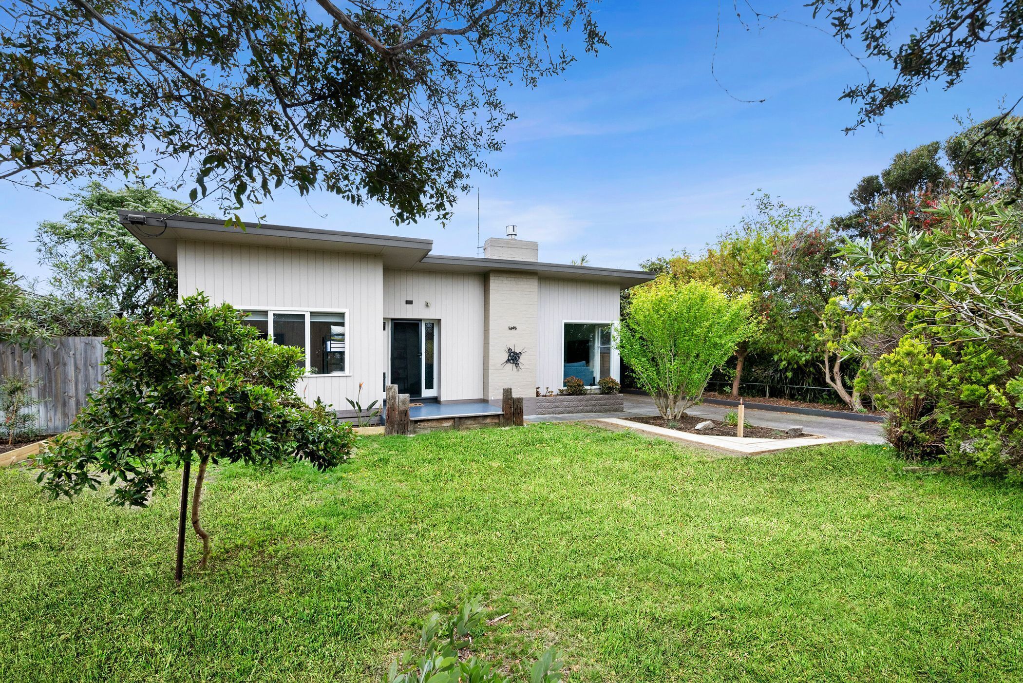 A modern two-story house with a well-maintained lawn and a small tree in the front yard.