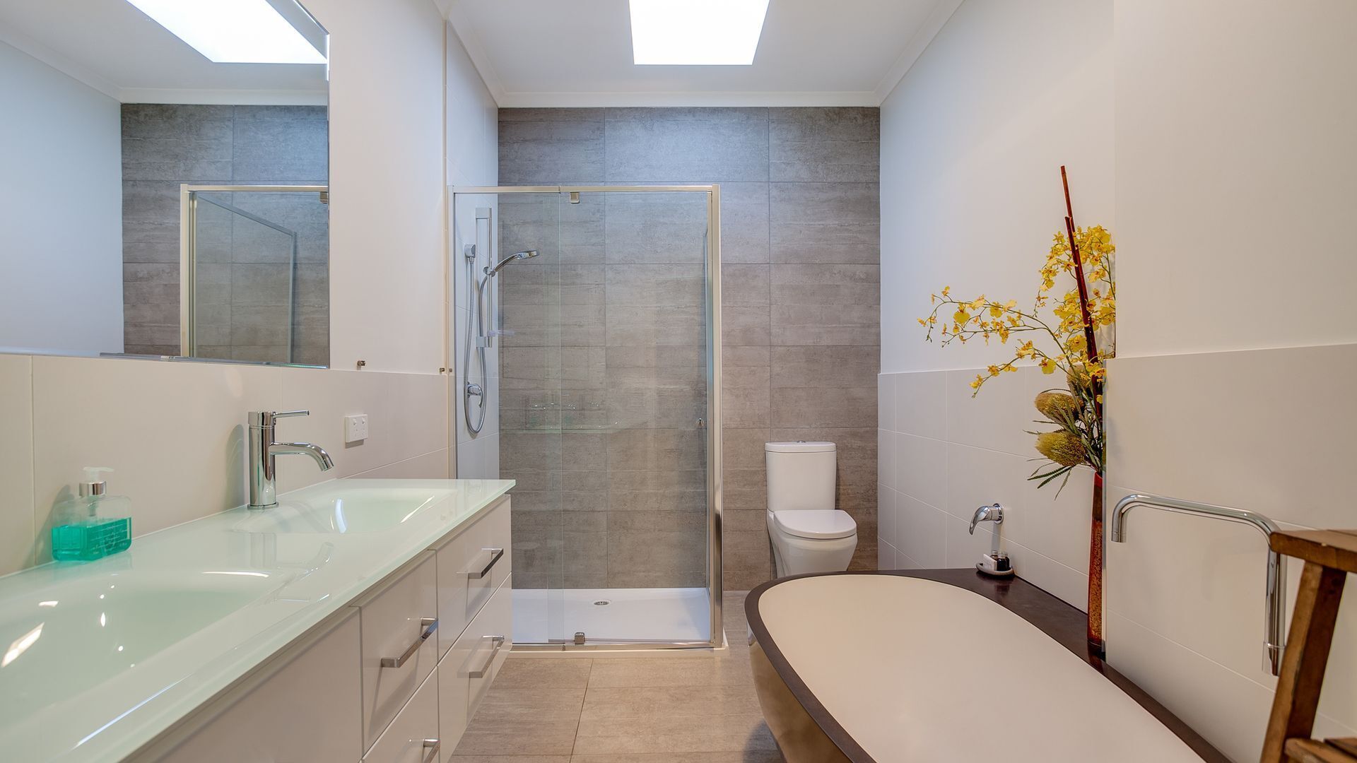 A modern bathroom with a glass-enclosed shower, a bathtub, and a vanity with a mirror.