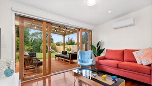 A modern living room with a red sofa, a blue armchair, and a glass coffee table. - RYE Classic- 4bed, perfect location-up to 13 guests, foxtel- BONUS* NIGHTS OFFER (Rye)