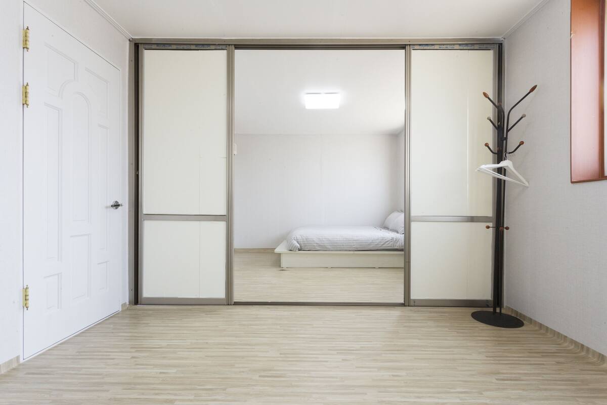 A room with a bed, a wardrobe, and a coat rack.