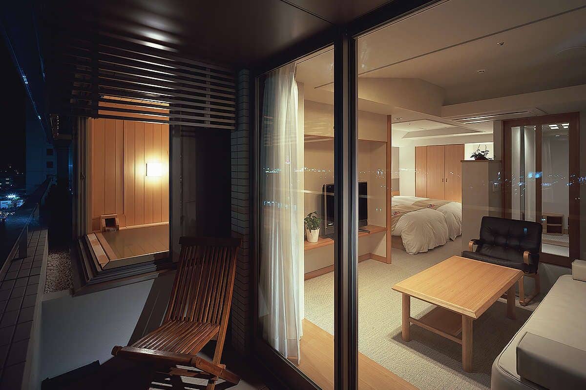 A modern interior with a sliding glass door leading to a bedroom with a bed and a sofa.