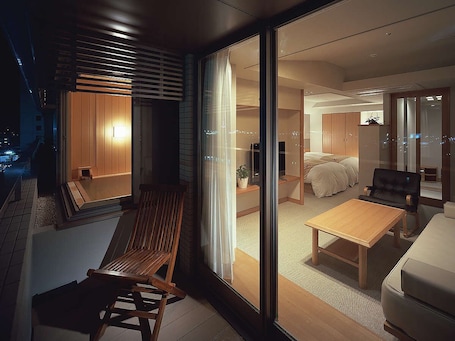 A modern interior with a sliding glass door leading to a bedroom with a bed and a sofa.
