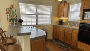 A kitchen with wooden cabinets, a granite countertop, a built-in oven, and a window with blinds.