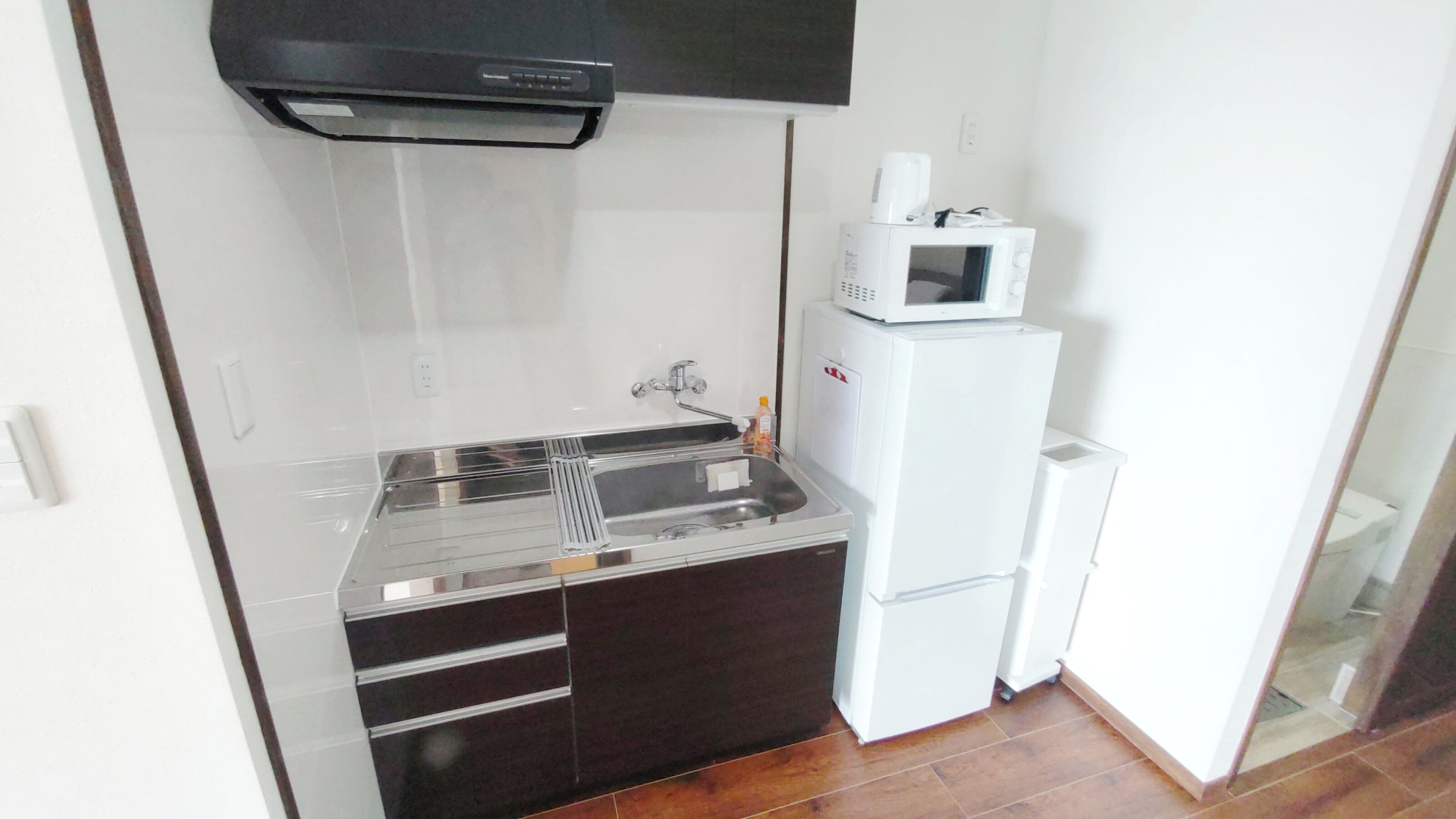 A compact kitchen with a stainless steel sink, a microwave, and a refrigerator.