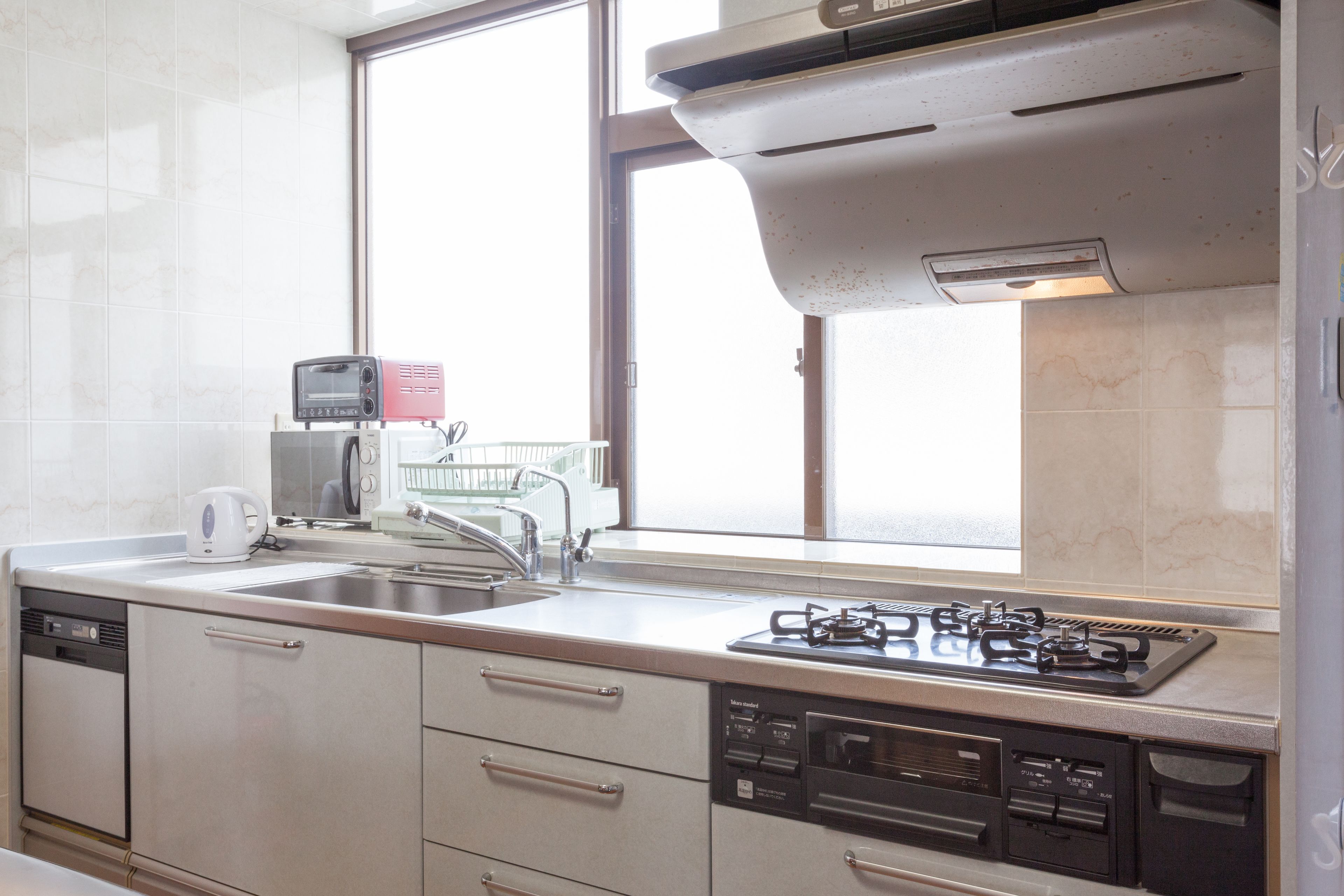 A modern kitchen with a gas stove, dishwasher, and a window providing natural light.