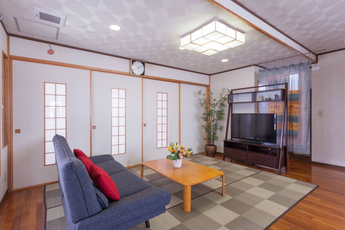 Una sala de estar con sofá, mesa de centro, televisor y puertas correderas.