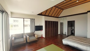 Una habitació àmplia amb un llit gran, un sofà i una televisió.