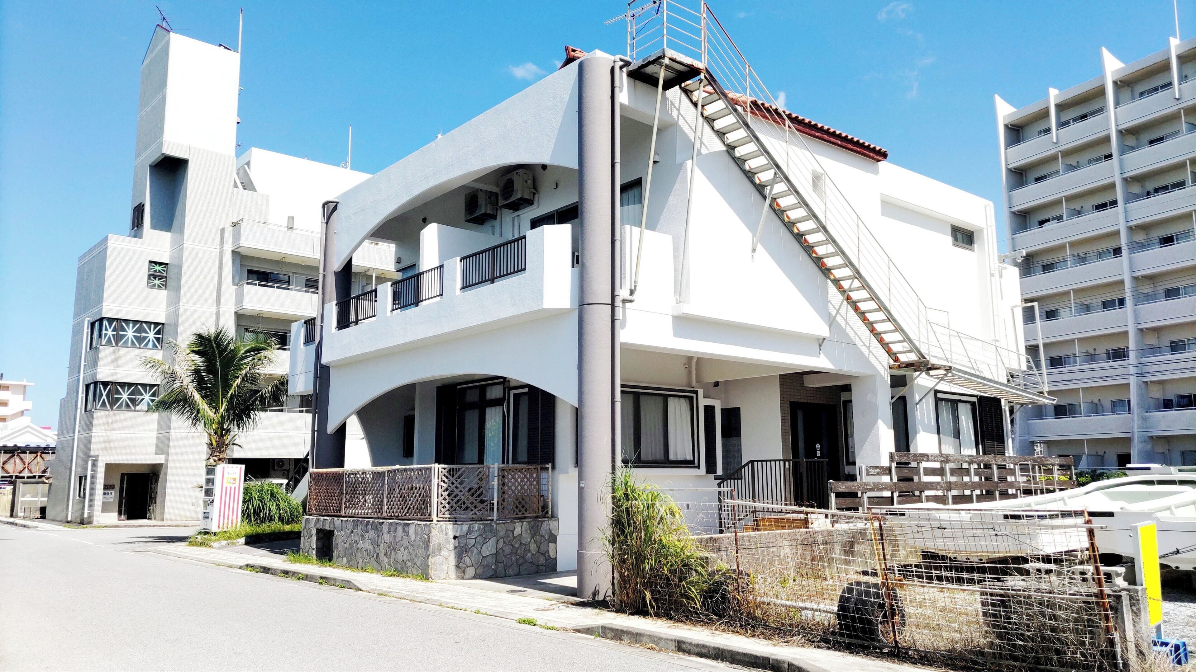 A modern two-story building with a unique architectural design, featuring a prominent staircase and a balcony.