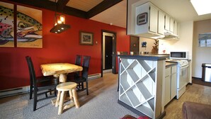 Una cocina funcional con comedor, que incluye una mesa y sillas de madera, una isla integrada con microondas y una pared de acento roja.