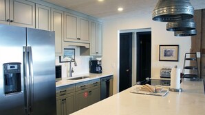 Une cuisine moderne dotée d’appareils électroménagers en acier inoxydable, de meubles de couleur claire et d’un plan de travail en marbre.