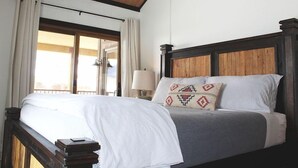 Un lit avec une tête de lit en bois, une literie blanche et un coussin à motifs.