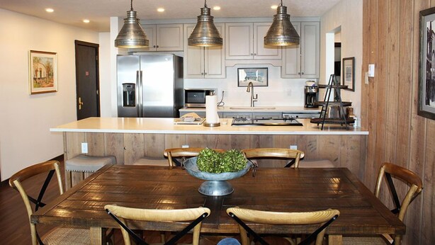 Une cuisine moderne dotée d’un îlot central, de luminaires suspendus et de meubles de rangement en bois.