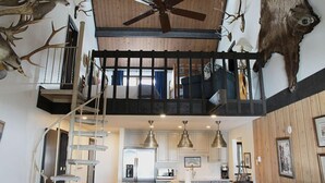 Un vaste loft doté d’une cuisine centrale, d’un escalier en colimaçon et d’un ventilateur de plafond.