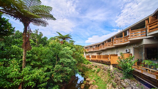 Un hôtel doté d’un balcon donnant sur une rivière, entouré d’une végétation luxuriante.