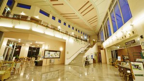 Un hall d’entrée spacieux avec un escalier, des coins salon et un comptoir d’accueil.