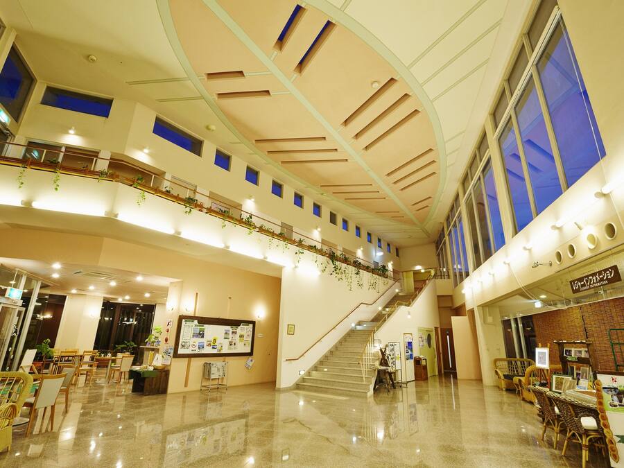 A spacious lobby with a staircase, seating areas, and a reception desk.