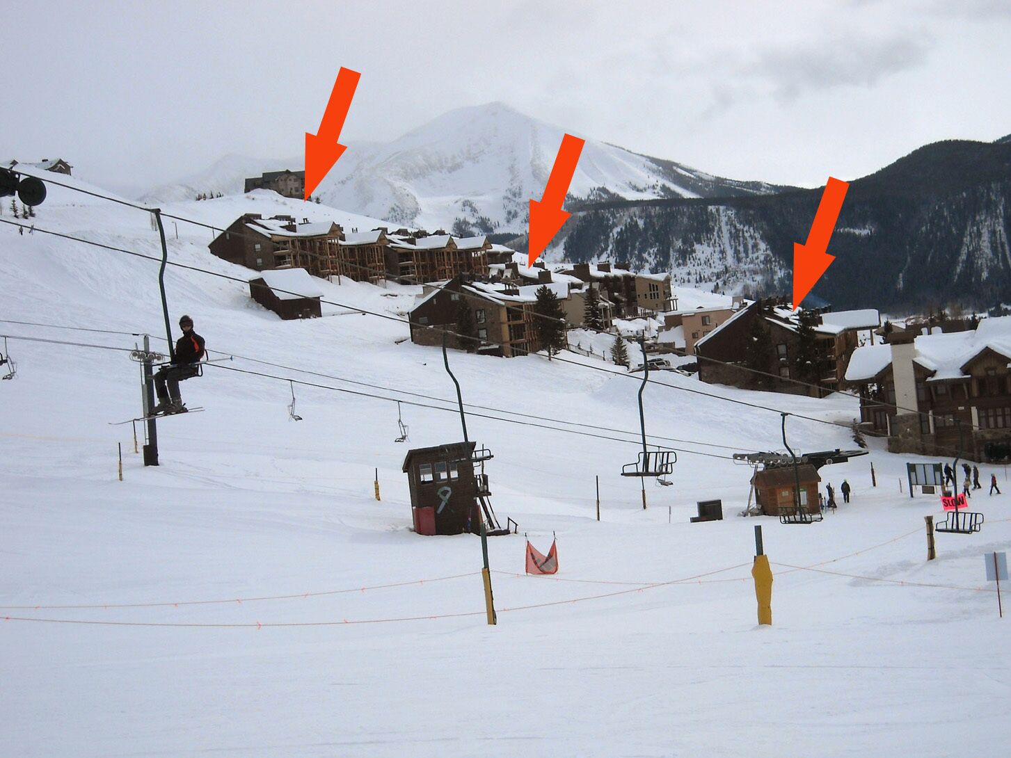 Une piste de ski avec des bâtiments en bois et un télésiège.