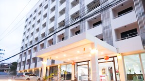 Un hotel moderno con entrada cubierta, varios pisos y un coche aparcado fuera.