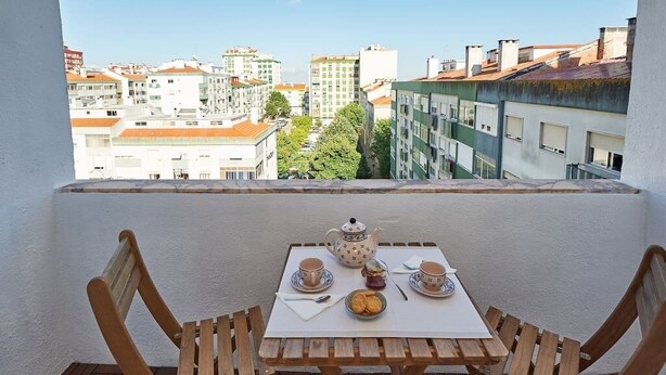 A balcony with a table set for two, featuring a teapot, cups, saucers, and a plate of cookies. - SEVEN GUEST HOUSE, a departing point to visit Lisbon and Sintra (Casal de São Brás)