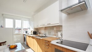 A modern kitchen with wooden cabinets, a stainless steel sink, and a built-in oven. - SEVEN GUEST HOUSE, a departing point to visit Lisbon and Sintra (Casal de São Brás)