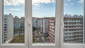 A view through a window of a multi-story building with parking in the foreground and other buildings in the background. - SEVEN GUEST HOUSE, a departing point to visit Lisbon and Sintra (Casal de São Brás)
