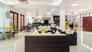A spacious lobby with a reception desk, seating area, and a dining setup. - The Mansion (Mabalacat City)