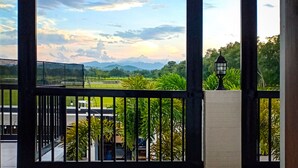A balcony with a view of a green landscape and mountains in the distance. - The Mansion (Mabalacat City)