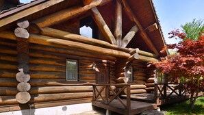 A log cabin with a wooden porch and a chimney. - Urube Village (Tsumagoi)