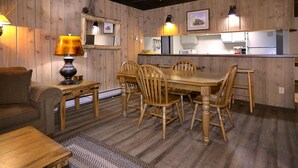 A rustic dining area with a wooden table and chairs, a sofa, and a lamp. - Great Location! Ski-In/Out Condo. Mountain Views, Fireplace. (Mt. Crested Butte)