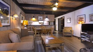 A cozy living room with a wooden dining table, a sofa, and a TV. - Great Location! Ski-In/Out Condo. Mountain Views, Fireplace. (Mt. Crested Butte)