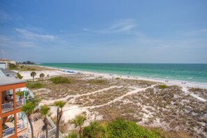 A beach view with a building featuring balconies and a sandy path leading to the shore. - Quiet Building in the Heart of Madeira Beach. Outstanding View. Beachfront Pool and Hot-Tub. (Madeira Beach)