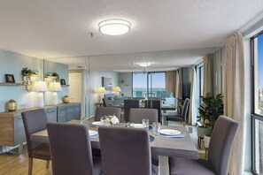 Un comedor moderno con una mesa grande, sillas y vista al mar.