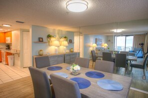 Ein stilvoller Essbereich mit einem Holztisch, grau gepolsterten Stühlen und blauen Platzsets.