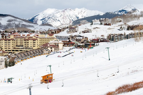 A snow-covered ski resort with multiple buildings, including a hotel with balconies and a ski lift area. - Great location! Ski-In/Out Dog Friendly Condo w/ Fireplace & Views (Mt. Crested Butte)
