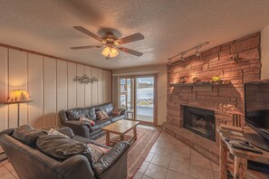 A cozy living room with a fireplace, leather sofas, a ceiling fan, and a large window. - Great location! Ski-In/Out Dog Friendly Condo w/ Fireplace & Views (Mt. Crested Butte)