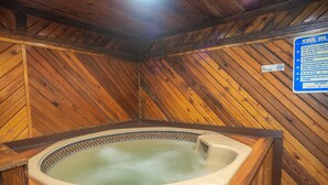 Ein Spa-Raum mit Holzwänden, einer Whirlwanne und einem Schild mit den Spa-Öffnungszeiten.