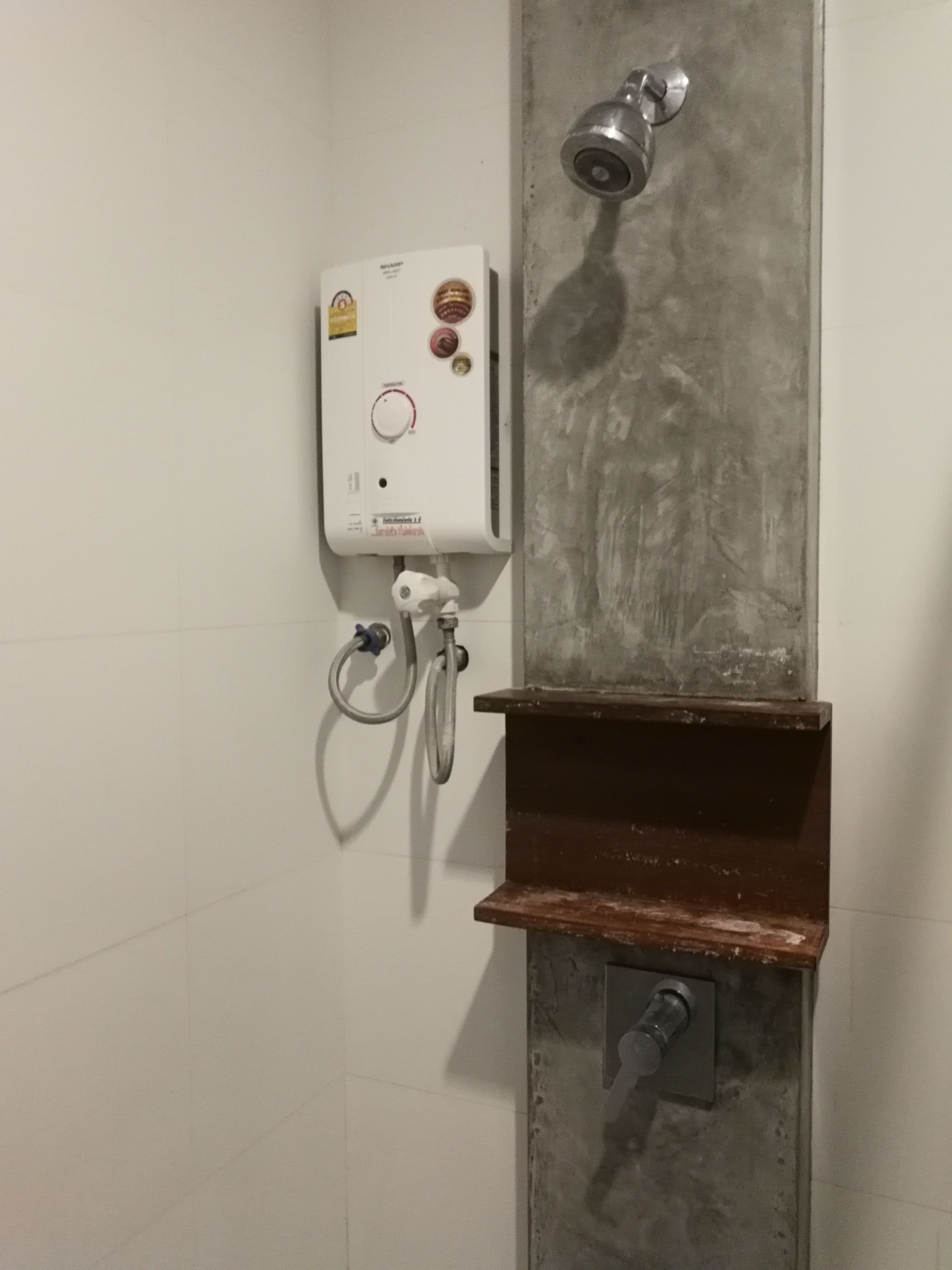 A shower area with a wall-mounted heater, a handheld showerhead, and a control panel.
