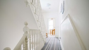 A staircase with white balusters leading to a room with a striped floor.
