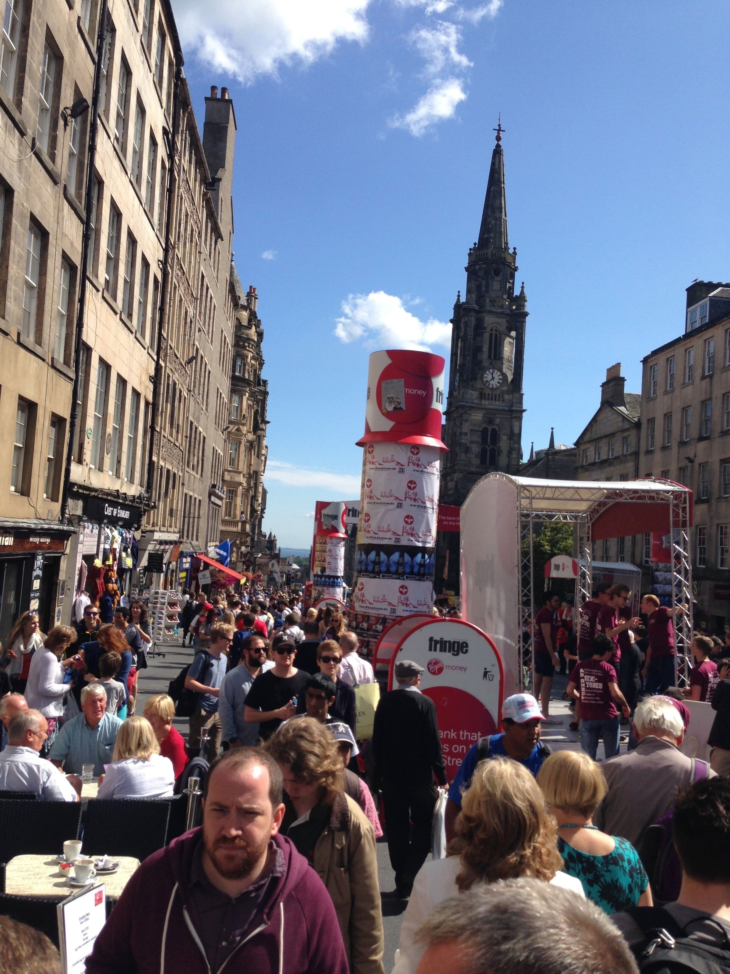 A busy street scene with people walking and a large red and white advertisement.