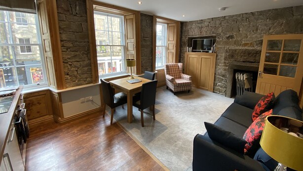 Una sala de estar acogedora con una pared de piedra, chimenea, televisor y comedor con mesa y sillas.