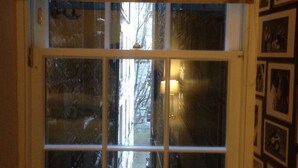 Una ventana de marco blanco y múltiples vidrios, que refleja una calle nevada y edificios exteriores.